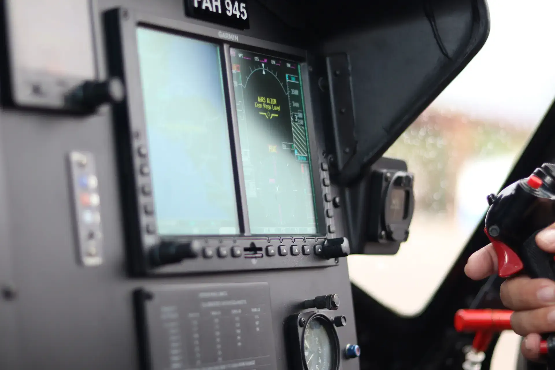 Close-up of an aircraft cockpit with a focus on avionic displays and pilot's hand on controls.