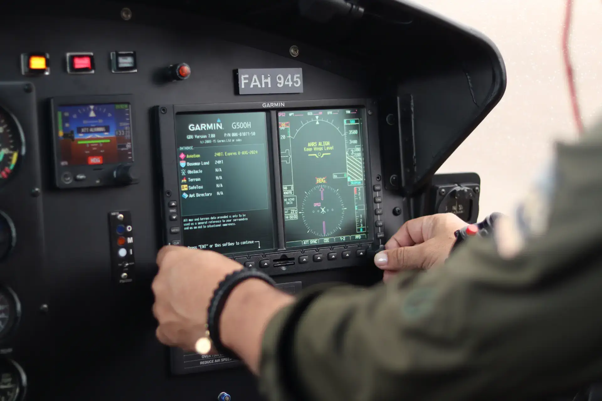 An aviation mechanic's hand adjusting controls on an aircraft's Garmin instrument panel.