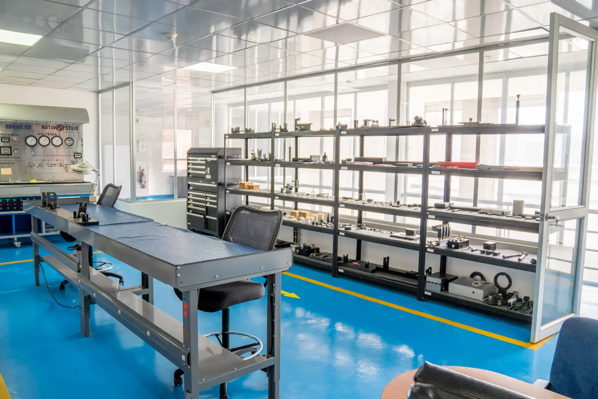 A well-lit industrial workspace with workbenches and shelves of mechanical parts.