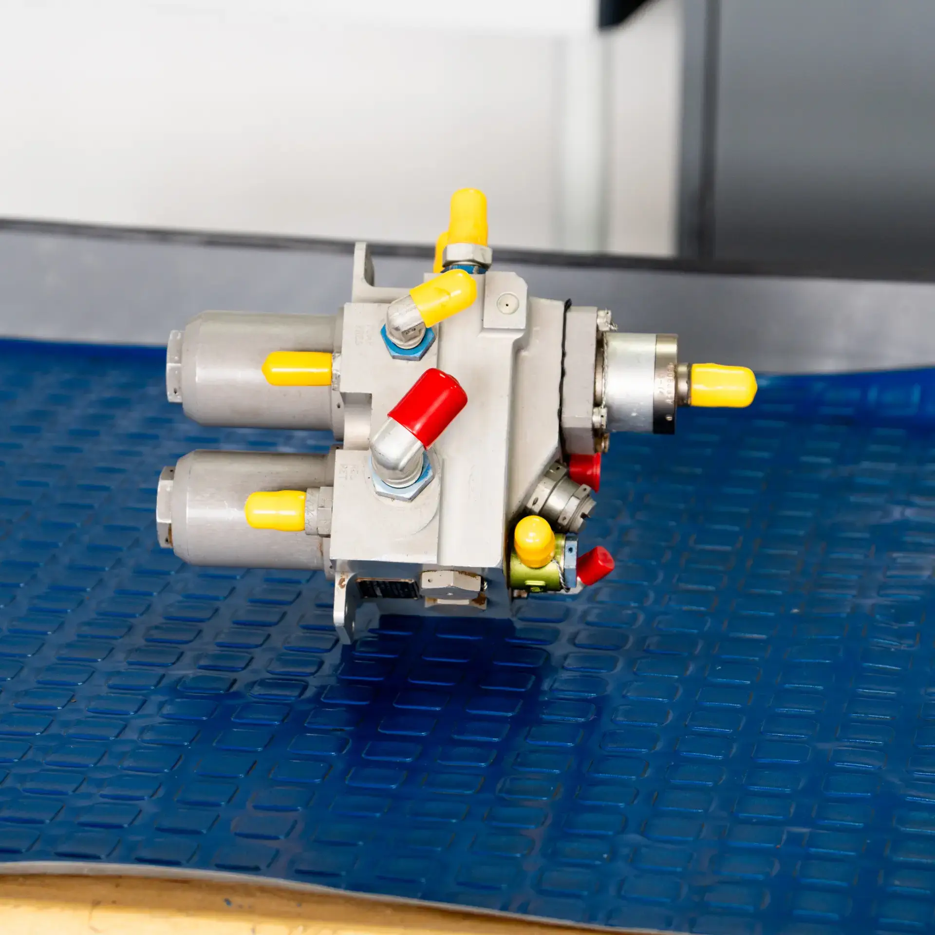 Aviation pneumatic equipment with yellow and red fittings on blue mat.