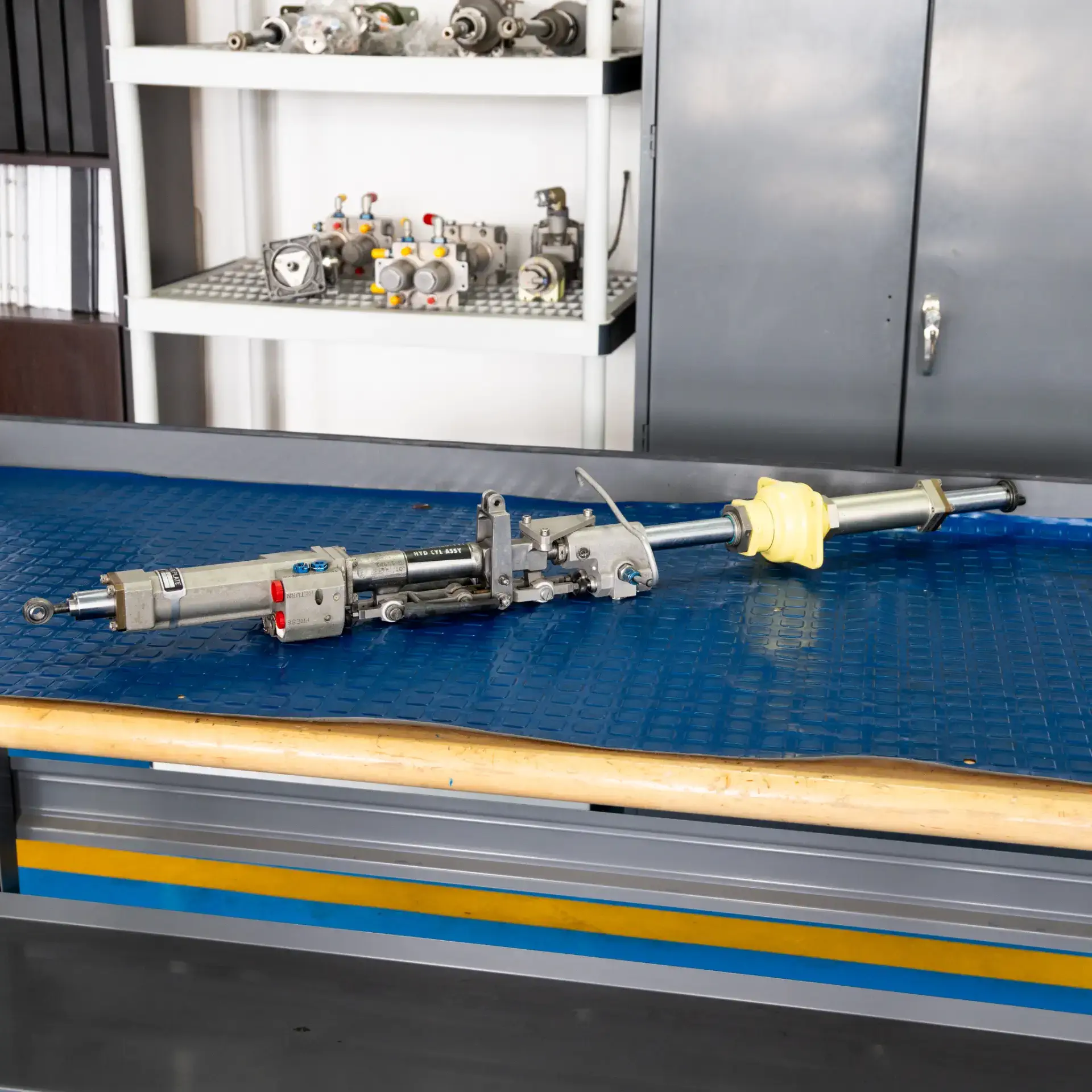 Aviation hydraulic equipment on a blue workbench with storage shelves in the background.