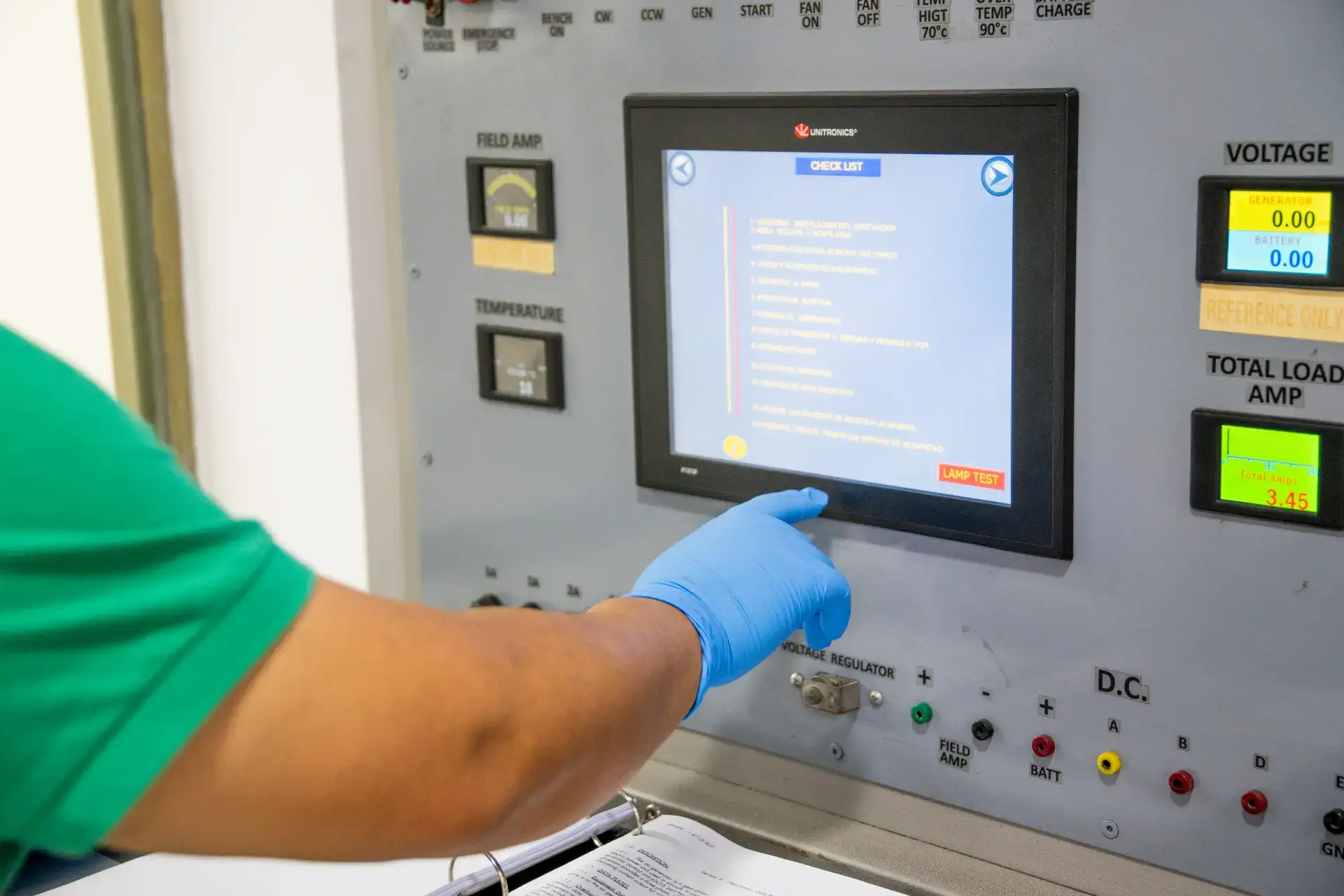 Person in green scrubs with a gloved hand touching a checklist on a touchscreen of industrial equipment.