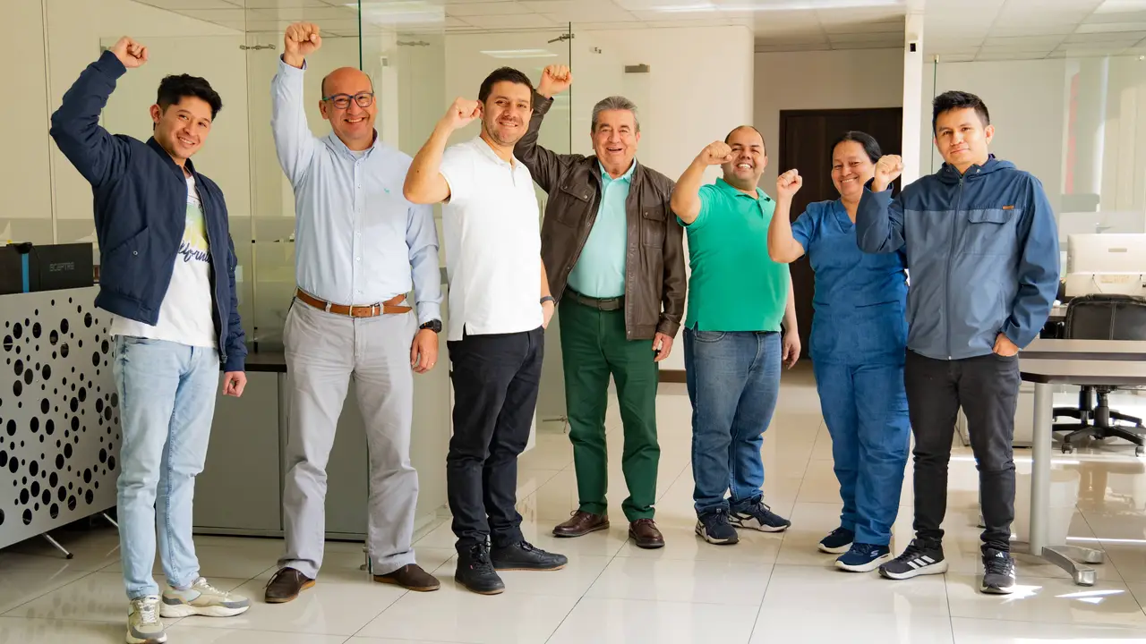 A group of individuals standing with fists raised in an office setting.