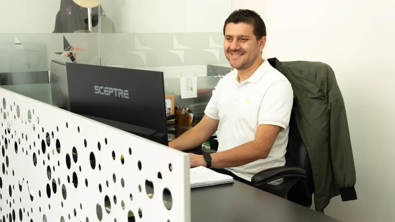 Person sitting at a desk with a computer monitor, working in an office environment.